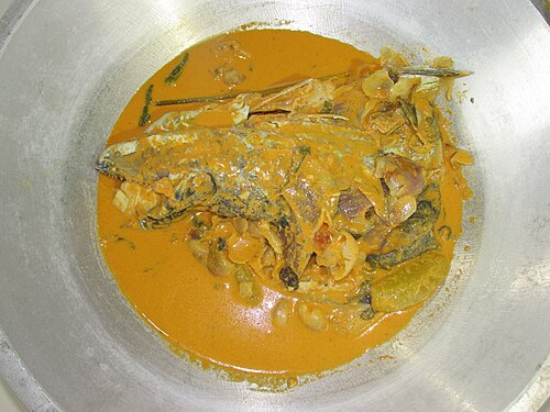 A plate of gulai kepala ikan (fish head's gulai) accompanied by ruku-ruku, slices of blimbi wuluh (Averrhoa bilimbi) and green cabai rawit (bird's eye chilies).