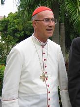 Tarcisio Cardinal Bertone in dress for hot tropical countries (white cassock with scarlet piping and buttons).