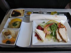 Business-class airline meal with tightly arranged plates, single-service condiments and serving tray