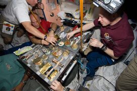 STS-129 crew members using specialised tableware for a meal in the International Space Station (2009)