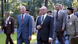 Carter, Begin, and Brzezinski walking together outside.