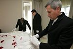 Hotel butlers-in-training arranging robes to lay over a bed.