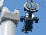 Components of a horizontal-axis wind turbine (gearbox, rotor shaft and brake assembly) being lifted into position