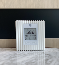 A self-calibrating Roomyou1 CO2 sensor with an e-ink screen. The device, which is powered by batteries, measures carbon dioxide, temperature, humidity, air pressure, and Melanopic Equivalent Daylight Illumination. It's designed for compliance with building standards like WELL.