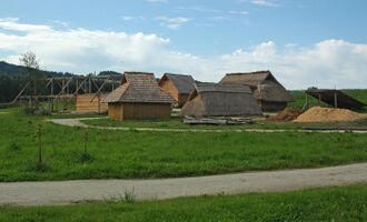 A group of wooden structures covered with shingles or thatch
