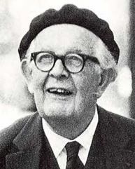 Photo of a man with white hair and glasses, wearing a suit