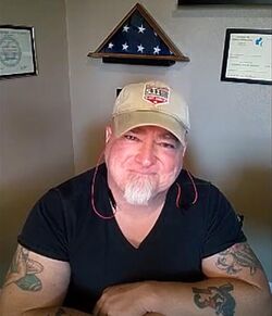 Photograph of Luis Elizondo showing crossed tattooed arms.