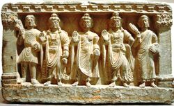 stone statue group, a Buddhist triad depicting, left to right, a Kushan, the future buddha Maitreya, Gautama Buddha, the bodhisattva Avalokiteśvara, and a Buddhist monk. 2nd–3rd century. Guimet Museum