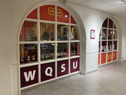 Two arched windows with orange and maroon decals and text that reads WQSU, The Pulse, 88.9