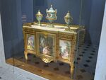 Louis XVI style commode of Madame du Barry; by Martin Carlin (attribution); 1772; oak base veneered with pearwood, rosewood and amaranth, soft-paste Sèvres porcelain, bronze gilt, white marble; 87 x 119 cm; Louvre[58]