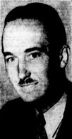 Black-and-white photographic portrait of a smiling man with slicked-back hair and a divided toothbrush mustache.