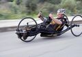 A recumbent racing handcycle with a streamlined frame and thin road racing wheels.