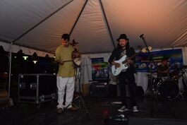 A man playing Sarangi alongside a man playing electric guitar in a concert in Baltimore, USA