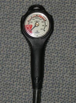 A pressure gauge with a rubber protective housing and flexible high-pressure hose which would be connected to the high-pressure port of the regulator first stage, so that the internal pressure of a diving cylinder can be monitored throughout a dive. The low-pressure area of the face is coloured red to indicate that the pressure may be too low to safely continue diving.