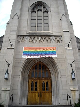Pride flag banner hung over the entrance to the Church of the Pilgrims in Washington, D.C. with the words "ALL ARE WELCOME" printed underneath