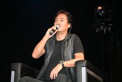 A man sitting in a chair and speaking into a microphone.