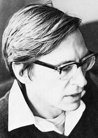 Black-and-white photo of a man with glasses wearing a collared shirt under a sweater