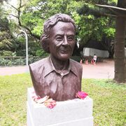 A bronze bust with flowers next to it, resting on a stone base