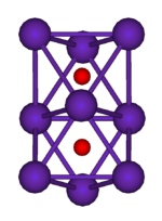 The ball-and-stick diagram shows two regular octahedra which are connected to each other by one face. All nine vertices of the structure are purple spheres representing rubidium, and at the centre of each octahedron is a small red sphere representing oxygen.