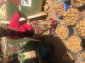 A woman at an outdoor market with buckets of potatoes for sale.