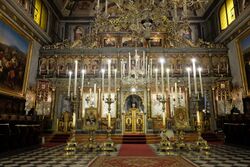 Picture showing the iconostasis of the Church of San Nicolò flanked by candles.
