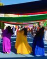 Women flip their hair sideways and wear brightly coloured traditional dress while performing an Emirati folk dance.