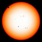 The sun in orange, as seen from the visible spectrum, with Venus in the top left quadrant