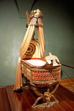 King of Rome's Cradle; by Pierre-Paul Prud'hon, Henri Victor Roguier, Jean-Baptiste-Claude Odiot and Pierre-Philippe Thomire; 1811; wood, silver gilt, mother-of-pearl, sheets of copper covered with velvet, silk and tulle, decorated with silver and gold thread; height: 216 cm; Kunsthistorisches Museum, Vienna, Austria[80]
