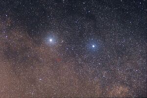 Two bright stars against a dense background of fainter stars, with one of the fainter stars circled in red