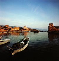 Small fishing boat and buildings lining harbour