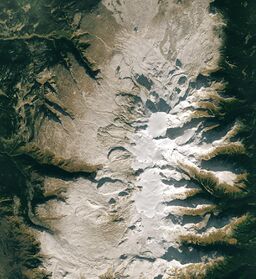 An overhead view of a barren, rocky plateau with a glaciated mountain in the middle.