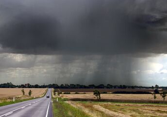 Late-summer rainstorm in Denmark . Nearly black color of base indicates main cloud in foreground probably cumulonimbus.