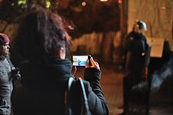 Image of a person using a smartphone to capture police interactions. Such recordings are frequently used in VDA studies to analyze human behavior and interaction. “Female using a smartphone to take