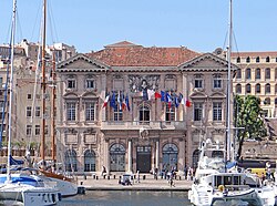 Die Fassade des Rathauses von Marseilles am Alten Hafen mit einigen Booten davor.