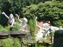Colour photograph of rockery from the side showing three ladies facing forward and up with their right hands raised