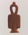 A red stone amulet shaped like a column with a looped top and two loops hanging at the sides
