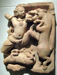 Carving in stone hanging from wall depicting a man fighting a horse.