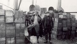 Salvage men photographed among the salvaged cases of whisky