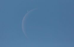 venus next to a crescent moon in the blue daytime sky