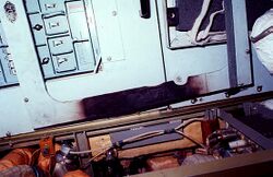A white panel covered in buttons, which shows signs of fire damage on its bottom edge. Wiring and other pieces of hardware are arrayed beneath the panel.