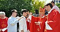 A Bishop anoints a young adult by using oil of chrism
